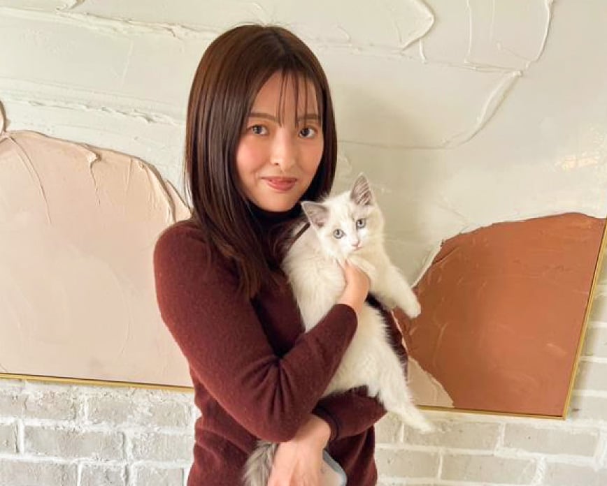 猫を抱えて笑顔を向けている